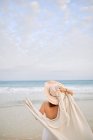 Back view female traveler in hat standing along seashore and looking away — Stock Photo