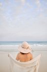 Вид ззаду жіночий мандрівник у капелюсі, що стоїть уздовж узбережжя моря і дивиться в сторону — стокове фото