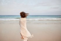 Vista posteriore viaggiatore femminile con cappello e camminare lungo la riva del mare e guardando altrove — Foto stock