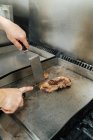Mão de chef irreconhecível cozinhar e cozinhar carne bovina no painel no restaurante — Fotografia de Stock