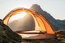 Tente de camping moderne placée sur une colline en terrain montagneux sur fond de lever de soleil dans les montagnes des Pyrénées — Photo de stock