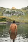 Back view of unrecognizable male traveler with naked torsi standing in Lacs d Ayous in highland terrain in Pyrenees — Stock Photo