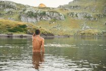 Back view of unrecognizable male traveler with naked torsi standing in Lacs d Ayous in highland terrain in Pyrenees — Stock Photo