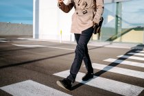Crop unrecognizable male entrepreneur in stylish outfit walking on crosswalk on sunny day in city — Stock Photo