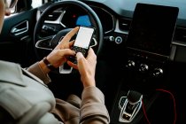 Ernte unkenntlich männliche Unternehmer sitzt auf dem Fahrersitz in Luxus-Automobil und surft Handy — Stockfoto