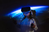 Chica joven irreconocible en ropa casual y auriculares VR conseguir una nueva experiencia y tocar el objeto virtual en la habitación con iluminación proyector de colores - foto de stock