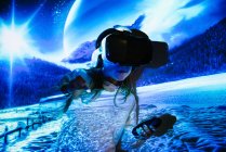 Unbekanntes junges Mädchen in Freizeitkleidung und VR-Headset macht neue Erfahrungen und berührt virtuelles Objekt im Raum mit farbenfroher Projektor-Beleuchtung — Stockfoto