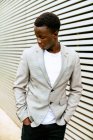 Vista lateral de um jovem afro-americano elegante que olha para longe de uma parede da cidade — Fotografia de Stock