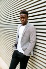 Vue latérale d'un jeune homme afro-américain à la mode regardant loin d'un mur de la ville — Photo de stock