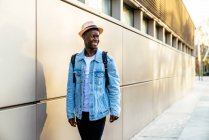 Young cheerful black male in denim jacket looking away with toothy smile in daylight — Stock Photo