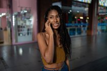 Портрет щасливої молодої африканської латиноамериканської жінки, яка розмовляє на смартфоні в комерційному центрі (Колумбія). — стокове фото