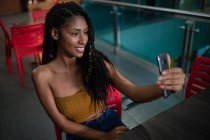 Retrato de atraente feliz jovem afro mulher latina usando um smartphone em um shopping comercial, Colômbia — Fotografia de Stock