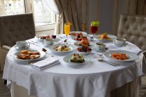 Various colorful dishes and juices served on round table during breakfast in elegant hotel restaurant in sunny morning — Stock Photo