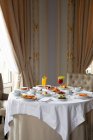 Vários pratos coloridos e sucos servidos na mesa redonda durante o café da manhã no elegante restaurante do hotel na manhã ensolarada — Fotografia de Stock