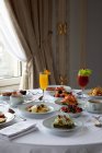 Various colorful dishes and juices served on round table during breakfast in elegant hotel restaurant in sunny morning — Stock Photo