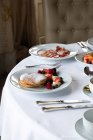 Vários pratos coloridos e sucos servidos na mesa redonda durante o café da manhã no elegante restaurante do hotel na manhã ensolarada — Fotografia de Stock