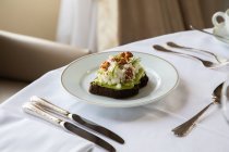 From above of healthy avocado toast with ricotta and walnuts placed on white plate and served on table in cafe during breakfast — Stock Photo