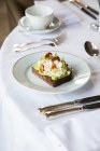 Сверху здоровый тост с авокадо с рикоттой и грецкими орехами на белой тарелке и подается на стол в кафе во время завтрака — стоковое фото