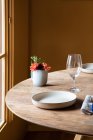 Tavolo servito con piatti in ceramica con posate su tovagliolo vicino agli occhiali da vino e fiori con frutta — Foto stock