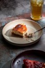 Сверху аппетитный пирог размещен на керамической тарелке со стаканом напитка со льдом в ресторане — стоковое фото