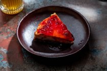 Сверху аппетитный пирог с ягодным вареньем помещен на керамическую тарелку со стаканом напитка со льдом в ресторане — стоковое фото