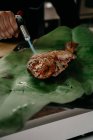 Zugeschnittene unkenntliche männliche Koch Kochen gebratenen Fisch mit Gasfackel während der Arbeit in Meeresfrüchte-Restaurant — Stockfoto