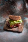 Hohe Winkel von appetitlichen Sandwich mit frischem Krustenbrot über Salatblättern und Speck auf Holzbrett — Stockfoto