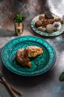 Desde arriba de baklava y galletas con té de menta marroquí cerca de cuchillo y tenedor colocado en la mesa decorada con hojas de menta - foto de stock