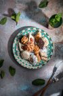 From above of baklava and biscuits with Moroccan peppermint tea near knife and fork placed on table decorated with mint leaves — Stock Photo