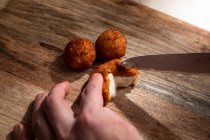 Von oben der Ernte anonymer Koch schneidet knusprige frittierte Käsekugel auf Holzschneidebrett — Stockfoto