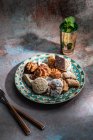From above of baklava and biscuits with Moroccan peppermint tea near knife and fork placed on table decorated with mint leaves — Stock Photo