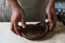 Сверху на урожай анонимный мужчина ремесленник прокатки глины кусок во время создания плиты в мастерской — стоковое фото