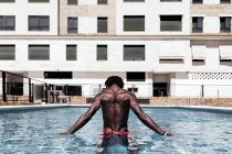 Homem afro-americano despreocupado de costas na piscina e desfrutando de férias de verão. — Fotografia de Stock
