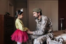 Військовий батько тримає руки маленької дівчинки перед тим, як піти захищати країну — стокове фото