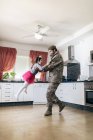 Cute daughter playing her father in military uniform in the kitchen — Stock Photo
