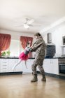 Fille mignonne jouant son père en uniforme militaire dans la cuisine — Photo de stock
