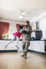 Fofa filha jogando seu pai em uniforme militar na cozinha — Fotografia de Stock
