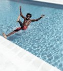 Verblüffter Afroamerikaner fällt in Shorts in Swimmingpool — Stockfoto