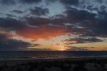 Malerische Landschaft von endlosem wogendem Meer mit Sandküste gegen erstaunlich bewölkten Himmel bei Sonnenuntergang — Stockfoto