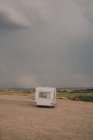 Camping-car stationné sur un terrain sablonneux contre un ciel nuageux en journée — Photo de stock