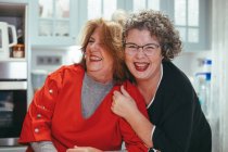 Glad middle aged lesbian woman embracing smiling female beloved in house — Stock Photo