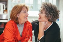 Frohe lesbische Frau mittleren Alters mit lächelnden Geliebten, die einander im Haus anschauen — Stockfoto