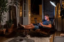 Entrepreneur masculin occupé assis dans un fauteuil et travaillant sur le projet tout en utilisant un ordinateur portable — Photo de stock