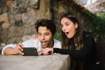Joven pareja mirando móvil mientras se divierten - foto de stock
