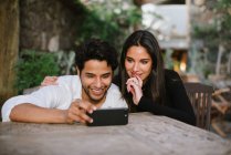 Молода пара дивиться на мобільний, розважаючись — стокове фото