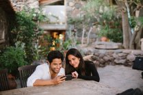 Jovem casal olhando para celular enquanto se diverte — Fotografia de Stock