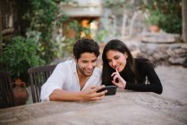 Молодая пара смотрит на мобильный, веселясь — стоковое фото