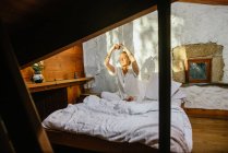 Homem loiro sentado em uma cama enquanto pratica meditação — Fotografia de Stock