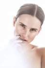 Mulher séria com maquiagem e sardas no nariz tocando suavemente a pele e olhando para longe — Fotografia de Stock
