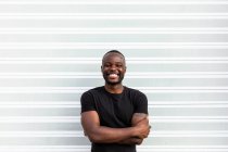 Content African American man in black t shirt standing looking at camera on light background — Stock Photo